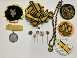 Merkantila klubben Åbo Akademi -erä sen toimintaan liittyviä yhden henkilön merkkejä; Ruusuke, kaulariipus, neulamerkit, mitali, kangasmerkit, tarra -osa hopeaa